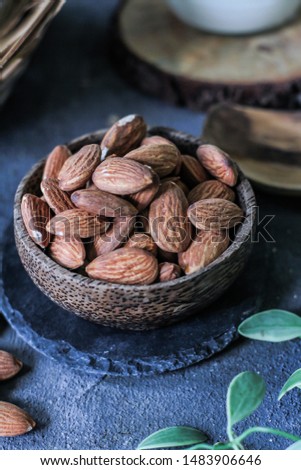 Photo of almond in a wooden bowl. Front View of almond. Almond with wooden spoon or scoop. Raw almond on the table. On rustic board. Images