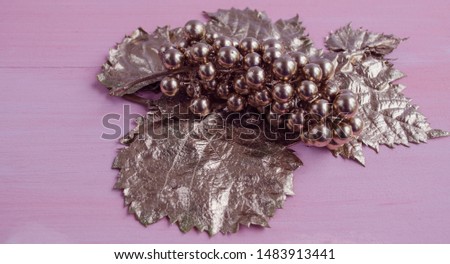 A bunch of grapes of bronze color on a pink background. Horizontal view