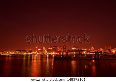 Boston at Night - A surrealistic view of Boston skyline and night light from the other side of the Boston Harbor. Special filter effect created a red colored sky and water reflections.