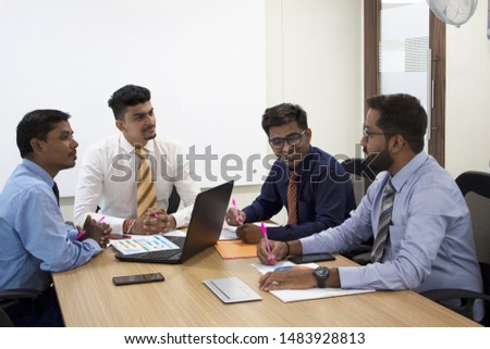 Team of four businessmen discussing at a meeting in office conference room Royalty-Free Stock Photo #1483928813