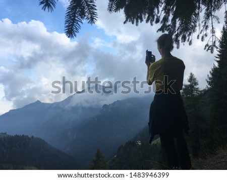 Hiker taking a picture with the smartphone of the Italian Alps