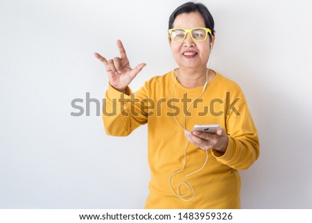 Senior asian woman listening to music with earphone,Elderly female using smartphone feeling funny and enjoying,Relaxing time,Happy and smiling