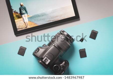 Top view modern camera and tablet with photos of a young woman by the sea.