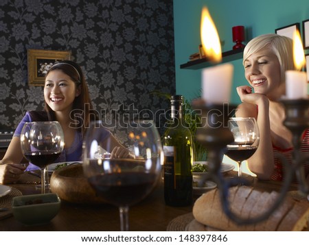 Smiling young multiethnic women enjoying dinner party