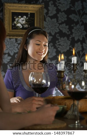 Happy young woman sitting with friends at dining table