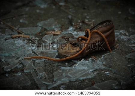 Old baby shoe on shattered glass. Picture taken outside an old orphanage in Denmark.