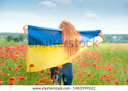 Girl carries fluttering blue and yellow flag of Ukraine in field. Ukraine's Independence Flag Day. Constitution day. Woman in traditional embroidery with flag of Ukraine. 24 August. Patriotic holiday.