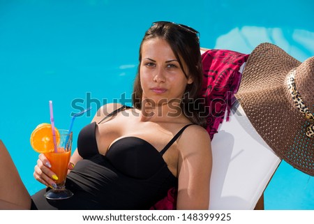 Young woman relaxing by the swimming pool enjoying her fresh cocktail