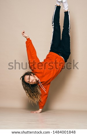A man in a red sweater is standing on one arm gymnastics sport fitness break dance                              