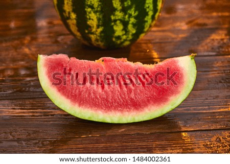 Fresh ripe striped sliced watermelon on wooden table with blurred garden sunset background. Food, Fruits or healthcare concept.