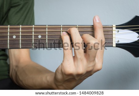 Guitar Player Hand or Musician Hand in F Major Chord on Acoustic Guitar String with soft natural light in close up view Royalty-Free Stock Photo #1484009828