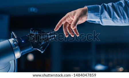 Futuristic Robot Arm Touches Human Hand in Humanity and Artificial Intelligence Unifying Gesture. Conscious Technology Meets Humanity. Concept Inspired by Michelangelo's Creation of Adam Royalty-Free Stock Photo #1484047859