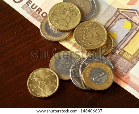 Money: euro coins and bills close up isolated on wood background