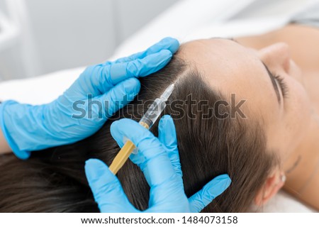 Beautician injections for healthy hair growth. Mesotherapy of the scalp. A young girl is undergoing a course of spa treatments in the office of a beautician. Moisturizing, cleaning and facial skin  Royalty-Free Stock Photo #1484073158