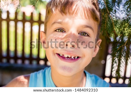 Close-up portrait of little boy in blue t-shirt with green eyes and crooked teeth. International childrens day Royalty-Free Stock Photo #1484092310