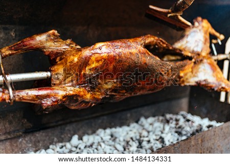 Spit-roasted meat whole lambs baked on a spit direct on fire outdoor