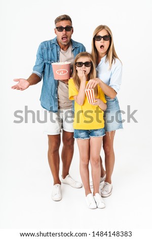 Photo of shocked family in 3D glasses holding popcorn bucket while watching movie in cinema isolated over white background
