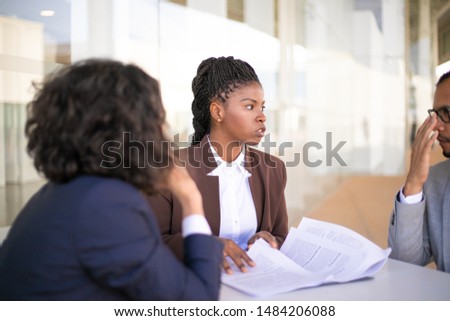 Confident female legal adviser checking customers documents. Multiethnic business man and women sitting at table and checking papers. Consulting concept
