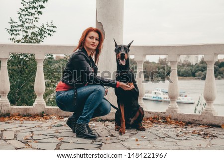 beautiful woman owner with her dog black doberman outdoor walking together