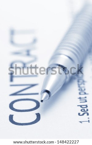 Close-up of silver pen on contract. Selective focus on top of pen. Toned image.