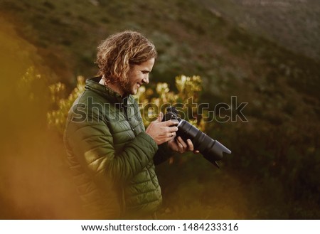 Smiling male photographer check photos on camera