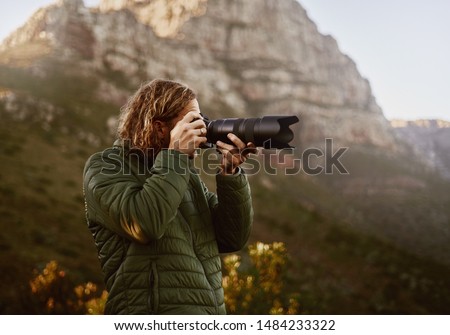 Young male photographer clicking photo from dslr camera
