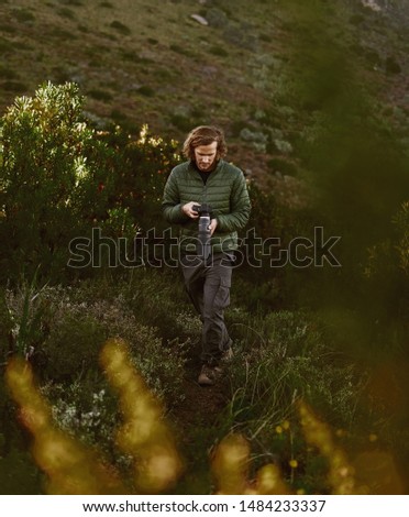 Male wildlife photographer with camera hiking in mountains