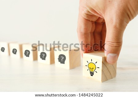 Business Concept image of revealing an idea, finding the right solution during creative process. Hand picking cube with bright light bulb