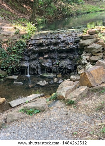 Beautiful pond with a small waterfall flowing off of the rock wall. The nature of this photo is just so peaceful and breath takings
