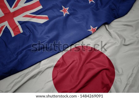 waving colorful flag of japan and national flag of new zealand. macro