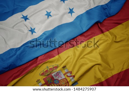 waving colorful flag of spain and national flag of honduras. macro