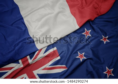 waving colorful flag of new zealand and national flag of france. macro