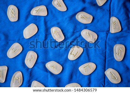 Bright blue fabric with rune stones on a table. Spirituality belief shaman. Conceptual objects nordic belief. Wiccan mystical ritual fortune telling. Esoteric magical background. 