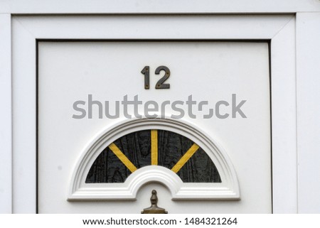 House number 12 on a white wooden front door