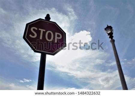 Stop sign with lamp post and clouds
