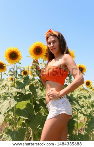 beautiful girl stands in a field of sunflowers back to camera in orange clothes