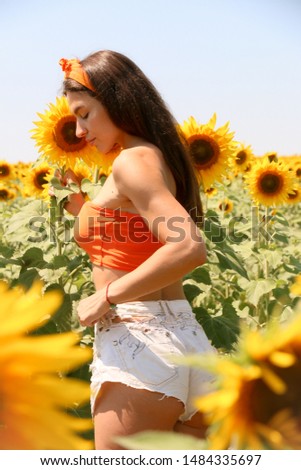 beautiful girl stands in a field of sunflowers back to camera in orange clothes