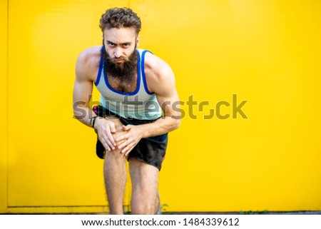 Portrait of an old-fashioned runner dressed in 80s style standing on the start position on the yellow background