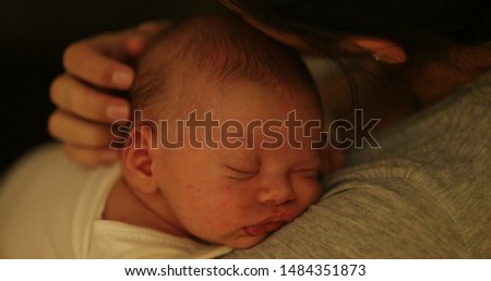 
Mother holding sleeping newborn baby kissing loving caring and affection