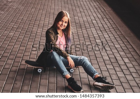Little pretty teenage girl is stting on the floor while posing for photographer in the tunnel.