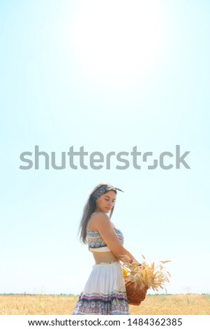 beautiful girl in an airy dress walking in a wheat field with a basket of spikelets in her hands