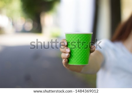 
Green glass of cardboard for coffee in a woman's hand.
