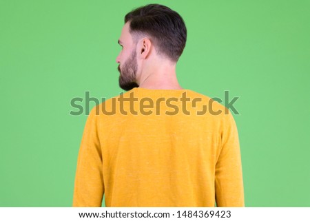 Rear view of young bearded man looking over shoulder