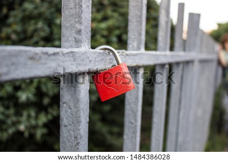 Red lock with a heart on a metal fence
