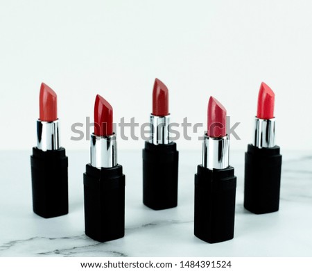 A set of luxury lipsticks in five shades of red and pink on white marble background, beauty care and fashion concept