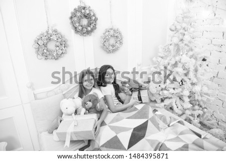 Opening presents on xmas eve. New Year surprise. Merry xmas and Happy New Year. Little children hold gift boxes. Little girls with presents in bed. Wait to play with toys til all the gifts are open.