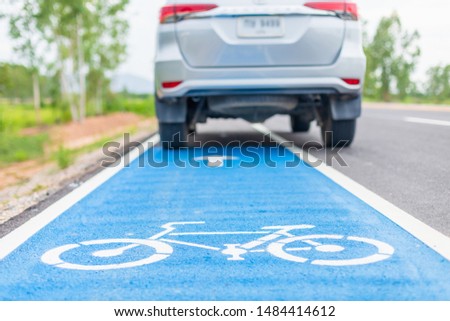 Modern SUV car running on asphalt road / bicycle lane and tread on white bicycle sign