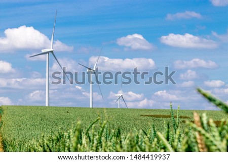 Wind turbines on a green wheat field producing power from renewable energy Royalty-Free Stock Photo #1484419937