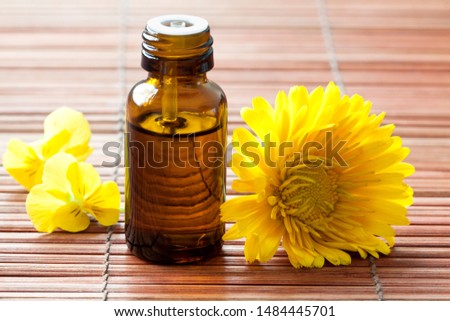 Bottle of essential oil and flowers on a bamboo background