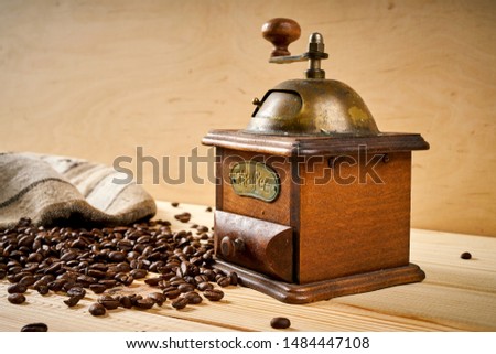 old brown coffee grinder on a wooden table with seeds